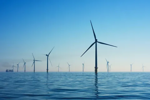 A dozen wind turbines over water
