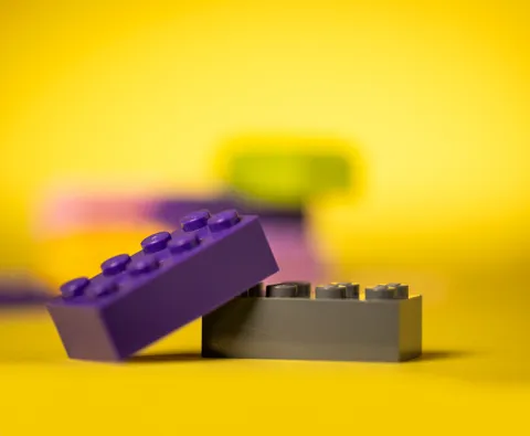 Close-up of purple and gray LEGO bricks against a gold background.