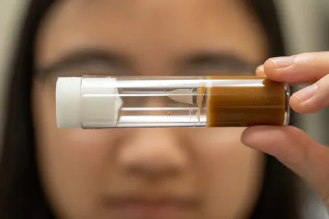 Researcher holding fruit fly in a cylinder