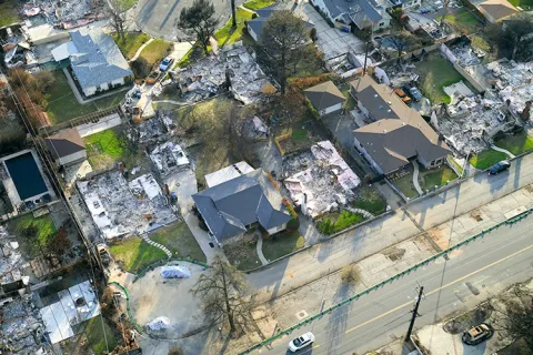 An aerial view of a neighborhood that has some homes completely burned to the ground and some left fully standing.