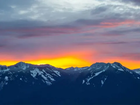 Sun rising behind snow-capped mountains