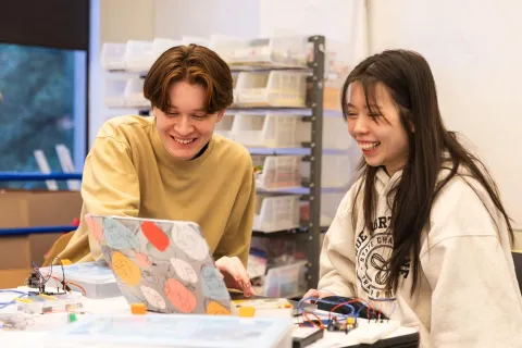 Two students laughing as they work on project in makerspace