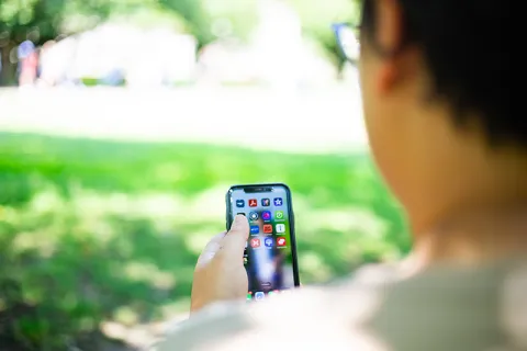 Person sitting outdoors on grass using a smartphone