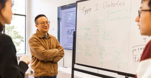 Three people working around whiteboard with type 1 diabetes and other formulas written on