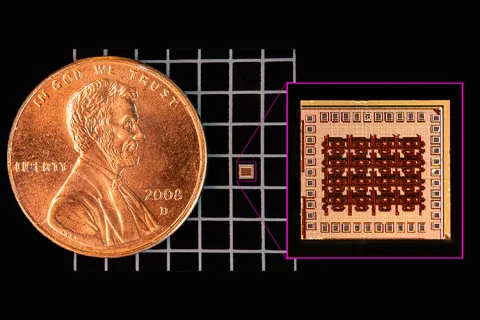 A close up of a penny on a black-and-white grid. To the right of the penny is a tiny microchip, about 1/20th the size of the penny.