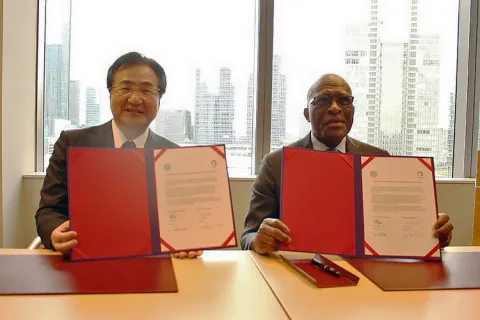Two men seated at a table holding signed agreements