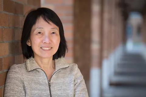 A head-and-shoulders photo of UW ECE Professor Lih Lin, standing in a brick hallway outside of the UW ECE building on the UW Seattle campus
