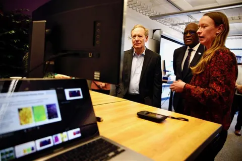 Three people looking at a computer monitor