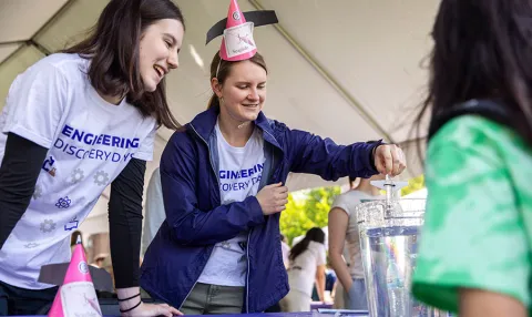 Two Engineering students demonstrating experiment to middle and elementary school students during Discovery Days