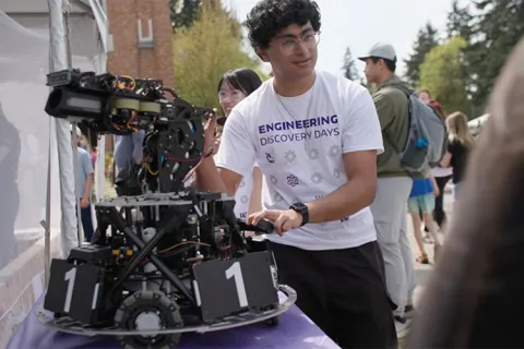 Engineering student showing off a robot to Discovery Days attendees