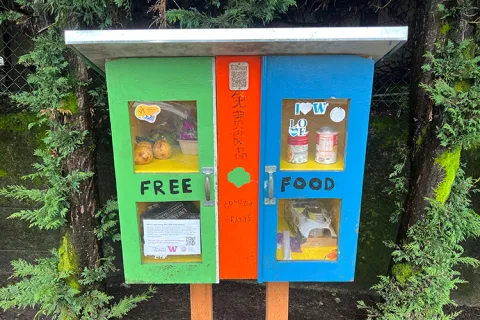 A colorful outdoor pantry with small windows showing various foods within.