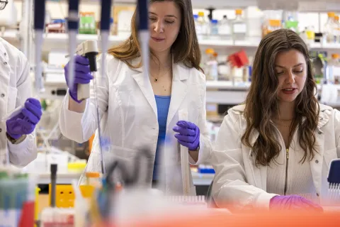 Two people wearing white lab coats run experiments