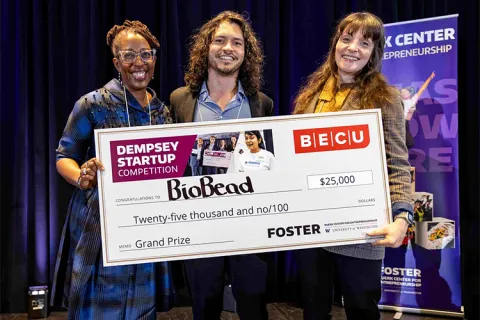 Three people holding up an oversized check