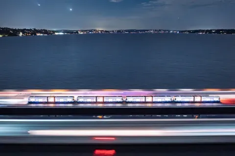 Aerial view of a light rail on a floating bridge at night