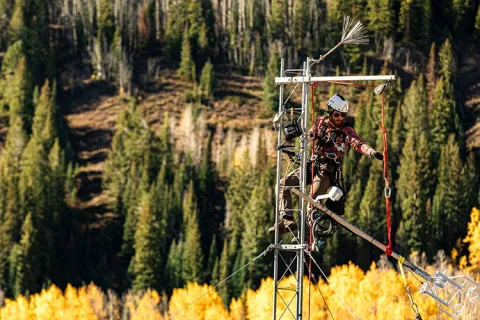 Environmental researcher working on an environmental monitoring tower in a forested landscape