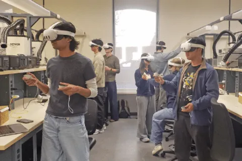 Students standing in lab wearing virtual reality headsets and holding controllers in their hands.