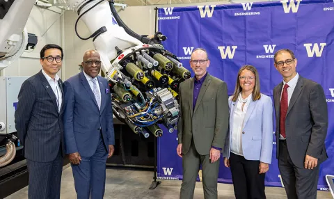 Group photo taken during UW event. Group is in front of large, advanced machinery