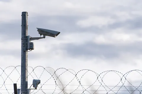 A camera above a barbed wire fence