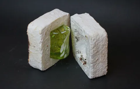 A small green glass sits in a white packing material.