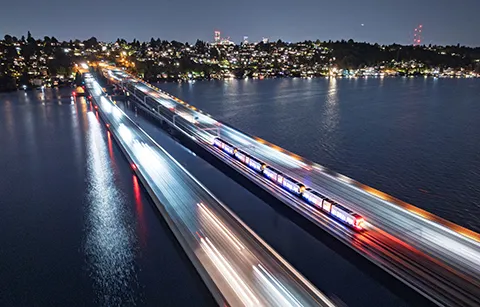 Aerial view of a light rail on a floating bridge at night