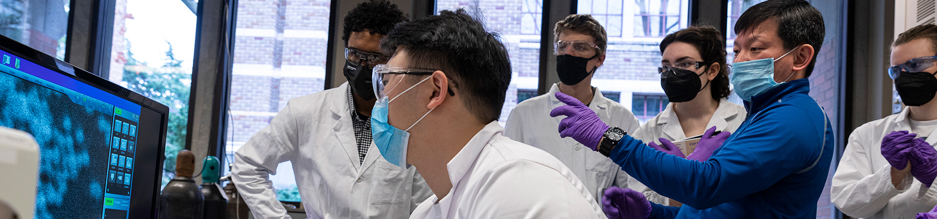 Three faculty in the lab with the faculty in the middle holding up a flask