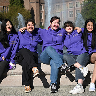 A group of students sitting side-by-side with arms on each other's shoulders
