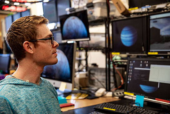 researcher looking at monitors showing planets