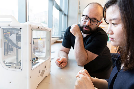 Two researchers looking at an electronic device