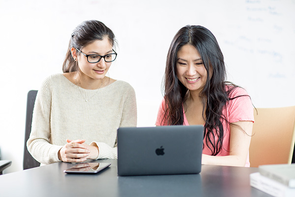 Two people sitting in front of a laptop