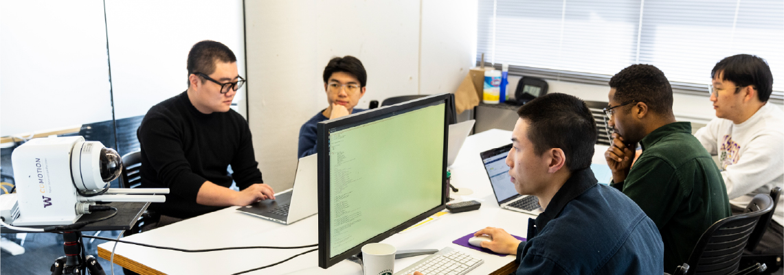 a group of men sitting at a desk with computers