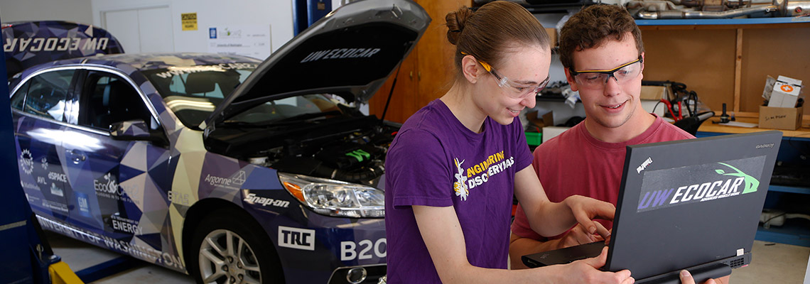 Two students looking at laptop working on ecocar project
