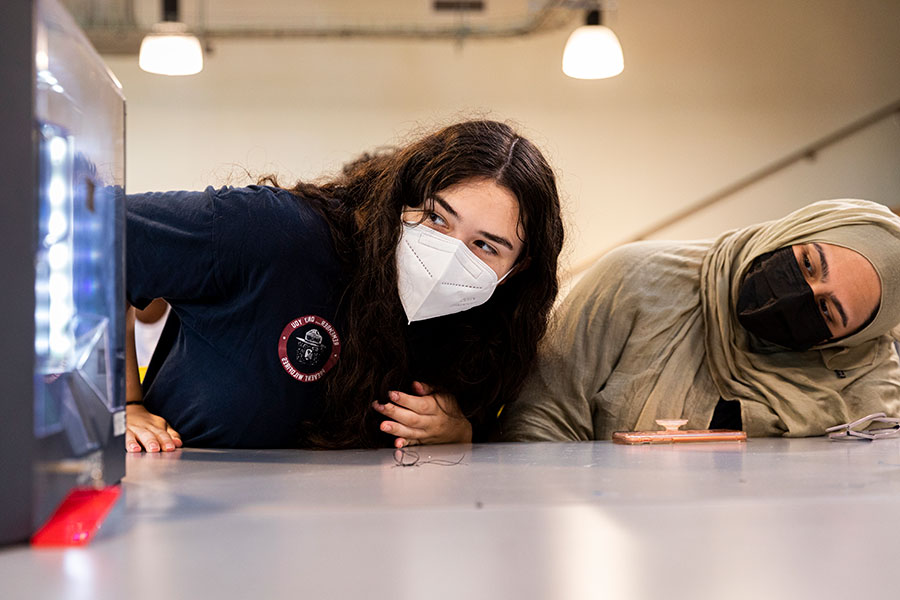 Two students looking sideways at lab equipment