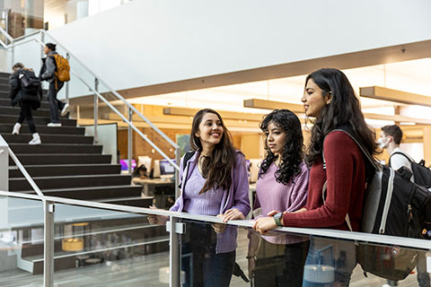 Three students standing together inside an academic building