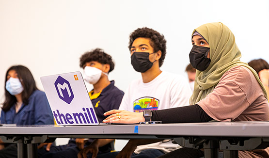 Group of students wearing masks sitting in classroom inside the MIL listening