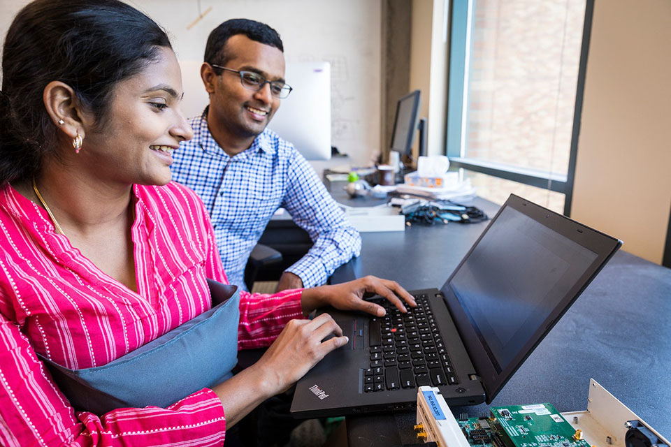 a woman and a man sitting at a table with laptop