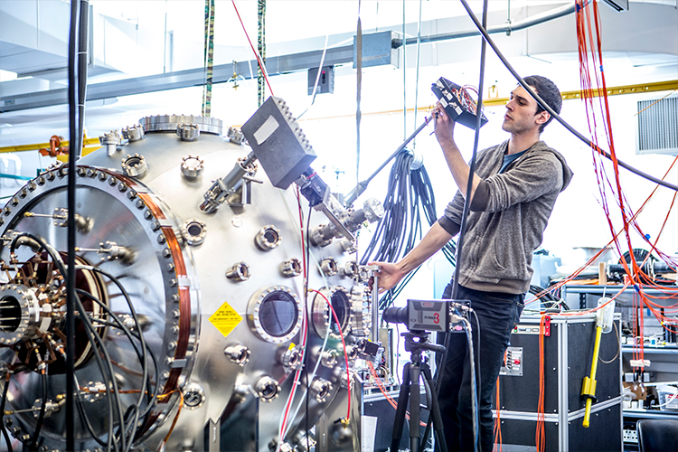 Third slide: Man in a lab adjusting cables on a machine