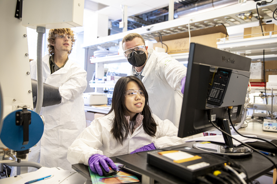 Three people in a lab looking at a computer