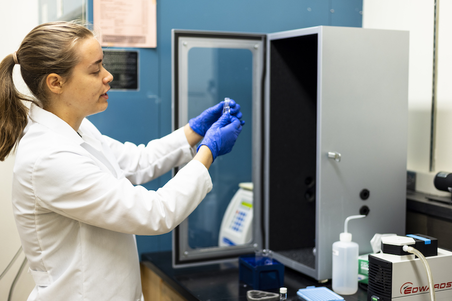 woman in a lab wearing gloves and holding a test tube