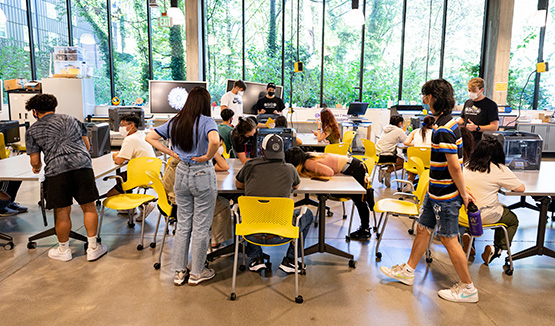 Students working in a classroom in groups in front of computer monitors