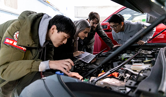 A group of students looking under the hood of an electric car