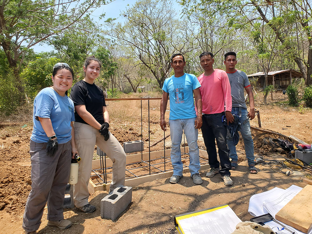 EWB team members Avocet Nagle-Christensen and Monika Kaneshige (left to right) and CAPS members work standing in front of two composting latrines.