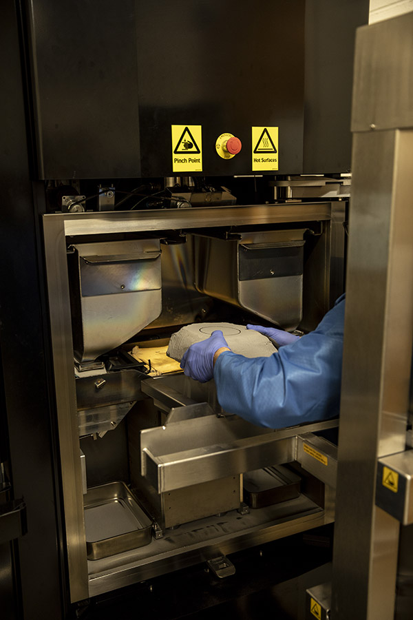 A lab engineer removing the titanium powder block from the printer after printing