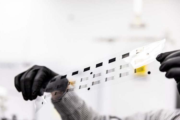 A hand in black glove holding up a strip of film