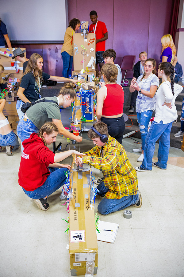 A group of students working together to build a Rube Goldberg inspired machine