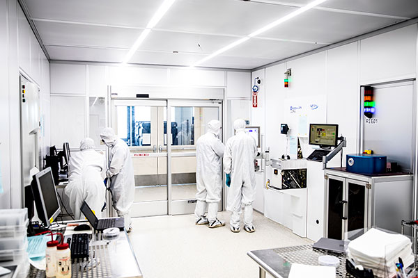 researchers in white cleanroom attaire inside a lab