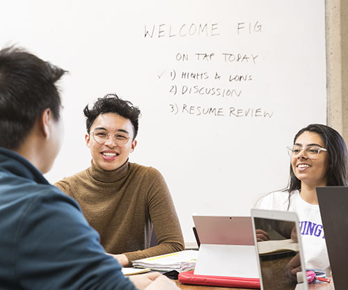 Miguel Monserate sitting at a desk with two students