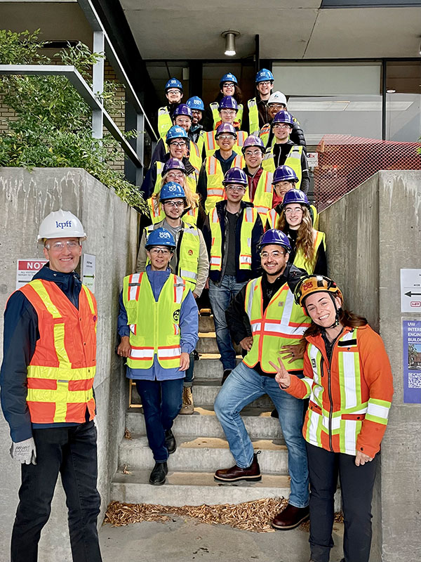 a group of people wearing safety vests and hardhats standing on the steps of the UW Club