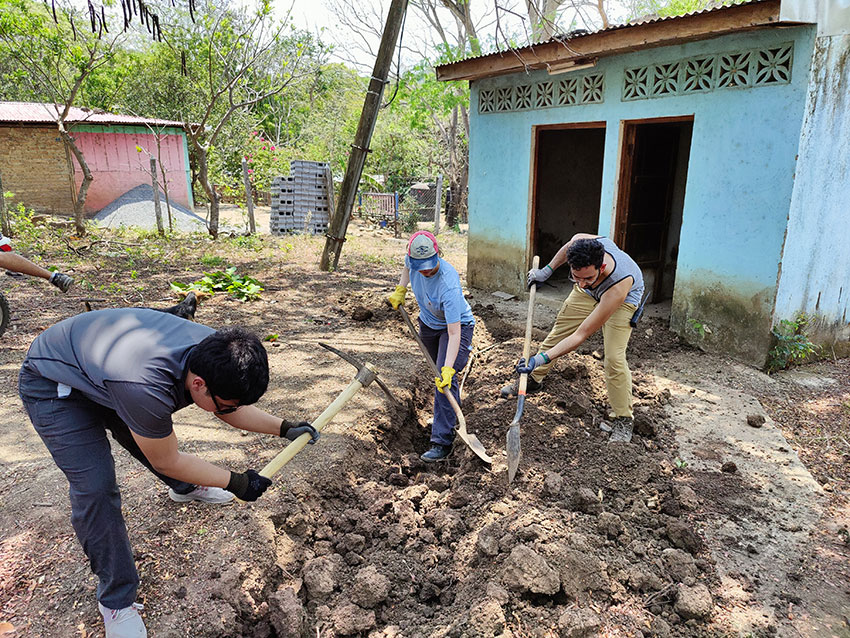 Three EWB students work on digging a trench