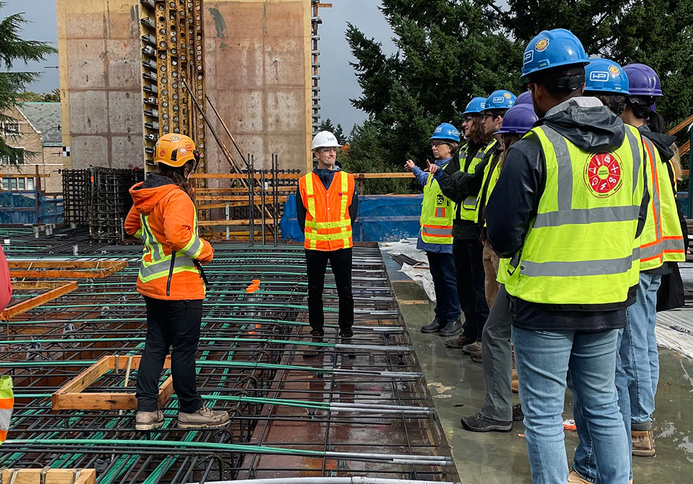 a group of people wearing safety vests and hardhats standing in the IEB construction site