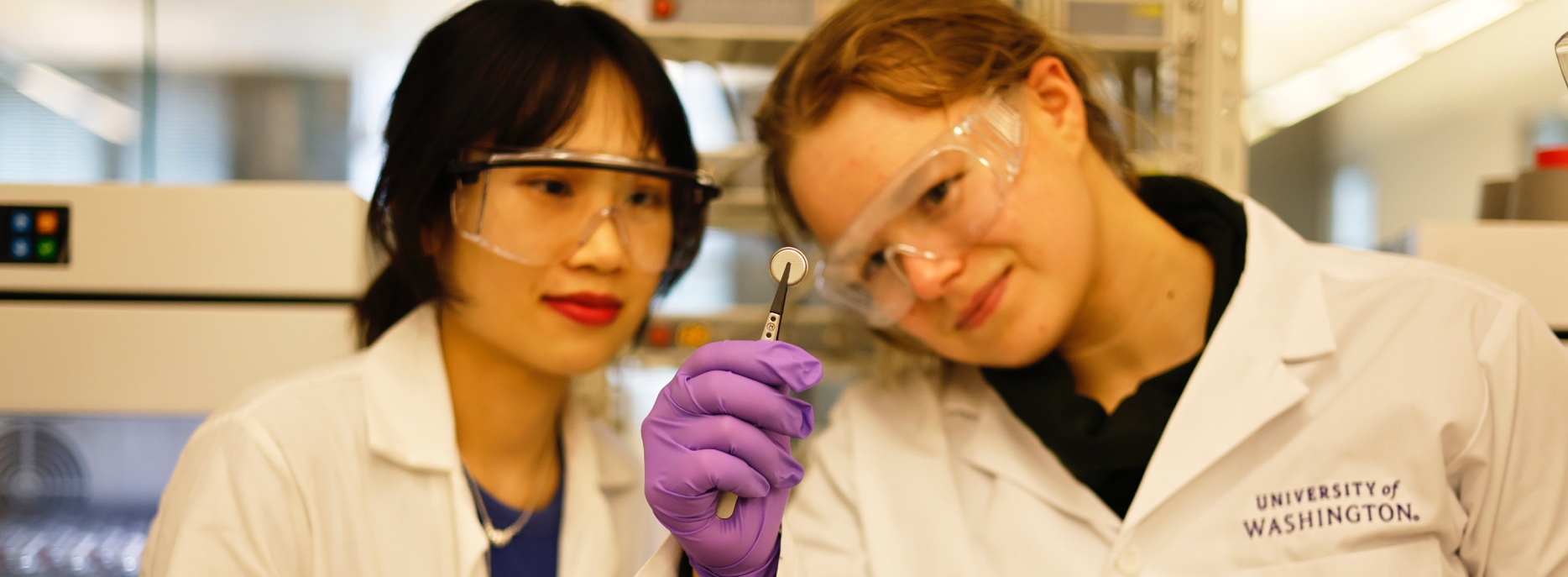 Students in a lab holding and looking at a round battery